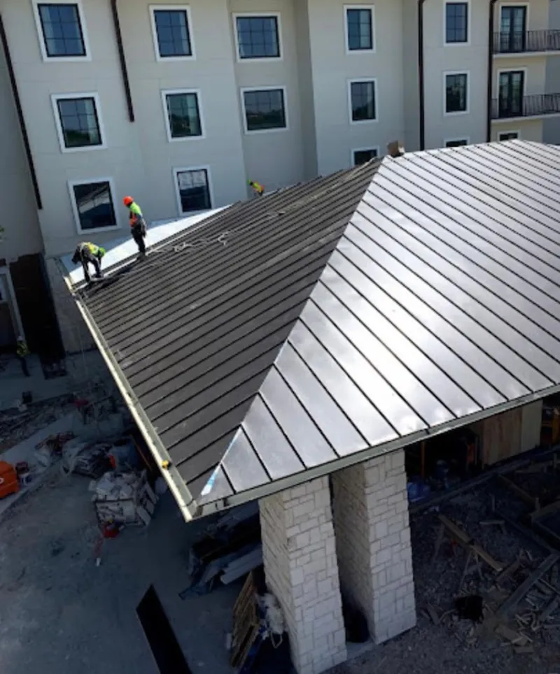 Crew installing standing seam metal roof panels on a commercial project in Algona